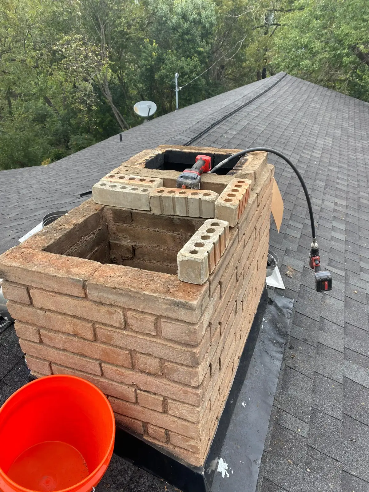 Brick chimney repair and masonry rebuild in progress on a Dallas roof