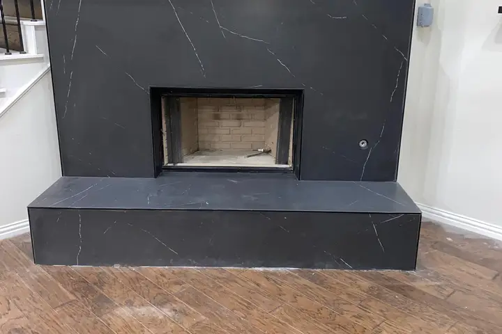Remodeled fireplace with a new dark stone surround in a Dallas home